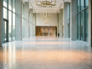 Leerer Hotellobby-Boden aus poliertem weißem Marmor mit modernen Säulen und warmem Licht aus deckenhohen Fenstern.