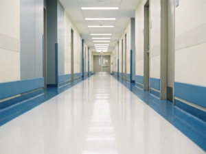 Leerer Krankenhausflur mit poliertem weißem Boden, der Neonlichter spiegelt, in sterilen Creme- und Grautönen mit Tiefenperspektive.