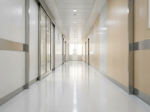 Leerer Krankenhausflur mit glänzendem weißem Boden und fluoreszierender Deckenbeleuchtung in moderner Klinikarchitektur.
