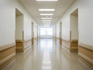 Leerer Krankenhausflur mit glänzendem Boden, der Neonlichter spiegelt, und weißen Wänden, die in heller Unschärfe verschwinden.