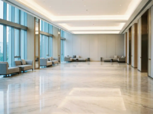 Leere moderne Hotellobby mit poliertem Marmorboden, raumhohen Glasfenstern und minimalistischen Möbeln in Elfenbein- und Champagnertönen.